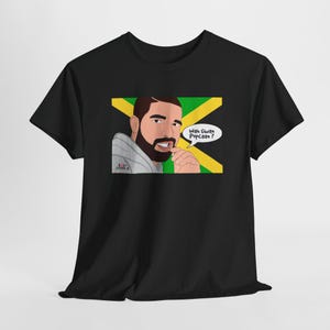 May include: Black t-shirt with a cartoon illustration of Drake wearing a grey hoodie and a Jamaican flag behind him. The text "Wah Gwan Popcaan?" is in a speech bubble above his head.