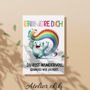 May include: A white card with a cartoon monster and a rainbow design. The card has the text "ERINNERE DICH" at the top and "DU BIST WUNDERVOLL, GENAUSO WIE DU BIST" below the monster. The card also has the text "Atelier ckiki" at the bottom.