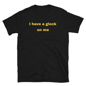 May include: Black t-shirt with the text "I have a glock on me" in yellow.