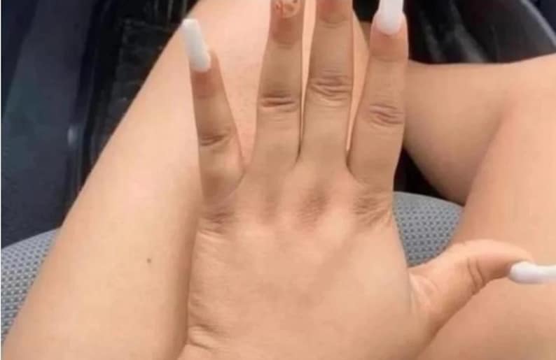 May include: A hand with long, white acrylic nails. The nails are square-shaped and extend past the fingertips. The skin tone is light brown. The image shows the hand in a relaxed position, with the fingers slightly spread.