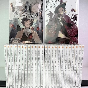 May include: A collection of manga volumes, featuring the series "Bungo Stray Dogs." The covers display character illustrations and the series title. The collection includes volumes 1-26, with two larger volumes on top. The text "10 Million" is visible on one volume.