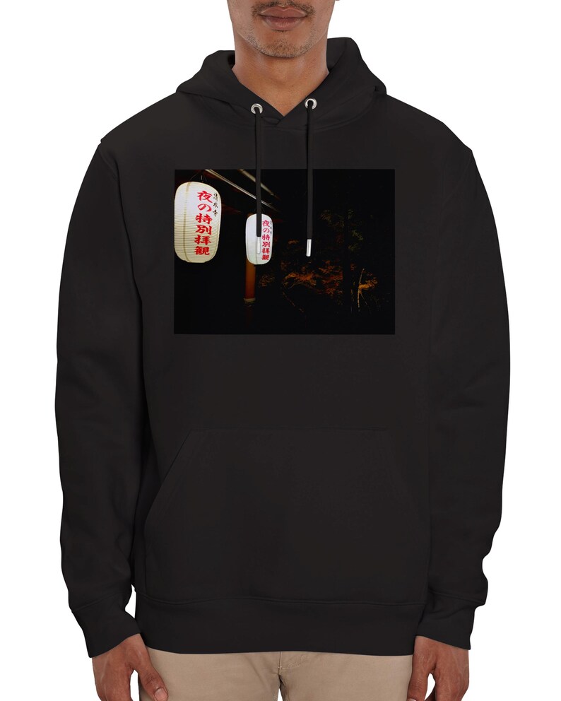 Pu&ograve; includere: Felpa con cappuccio nera con una grafica di due lanterne giapponesi bianche con testo rosso. Il testo sulle lanterne dice "夜のお祭り", che si traduce in "Festival notturno".