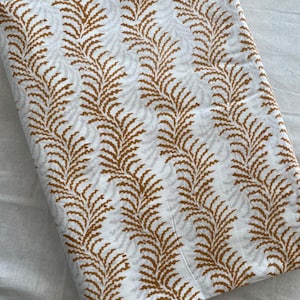 May include: White fabric with a repeating pattern of brown stylised fern leaves.