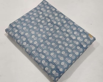 May include: A blue cotton fabric with a white floral pattern. The fabric is folded in half and has a smooth texture.