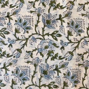 Könnte beinhalten: Ein Textilstoff mit einem sich wiederholenden Blumenmuster aus hellblauen und olivgrünen Blüten, die durch geschwungene olivgrüne Stängel und Blätter auf einem einfarbigen cremeweißen Hintergrund verbunden sind und ein durchgehendes botanisches Design bilden.