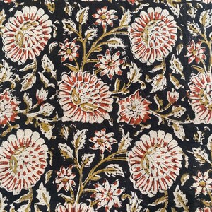 May include: Black fabric with a repeating floral pattern. The flowers are red, white, and cream with a brown outline. The background is black.