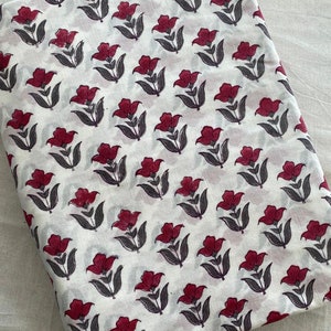 May include: White cotton fabric with a repeating pattern of burgundy flowers with grey stems and leaves.