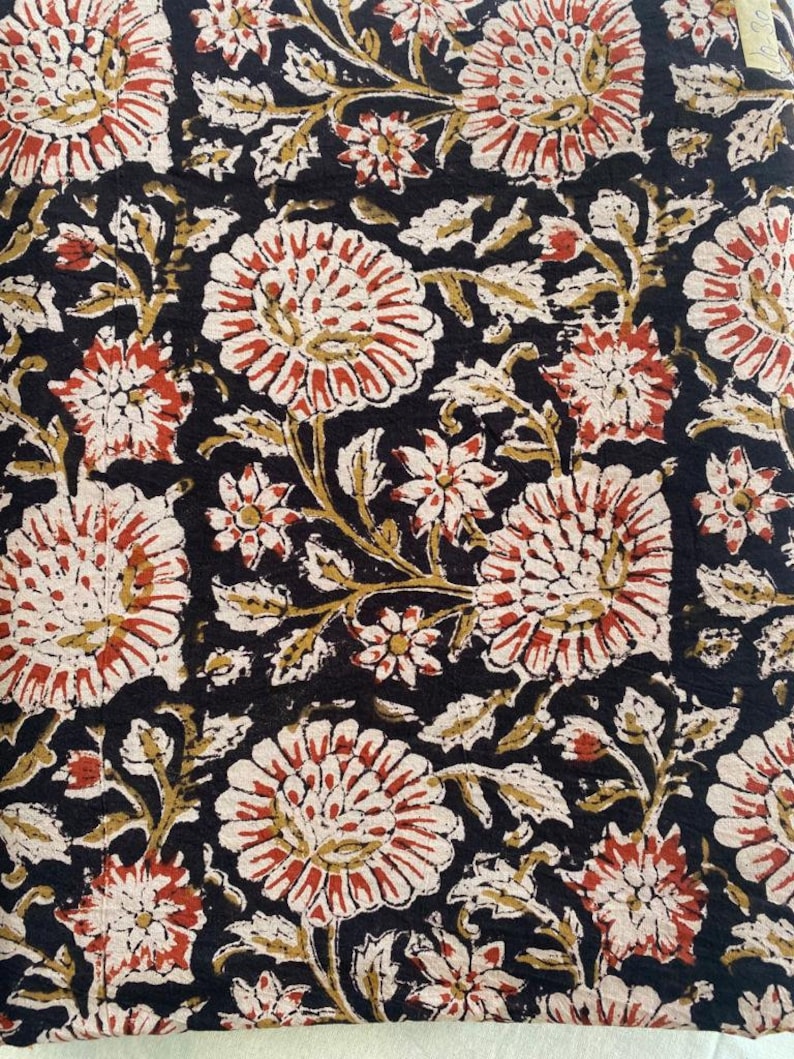 May include: Black fabric with a floral pattern in shades of red, white, and brown. The flowers are stylized and have a vintage look.