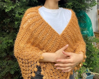 May include: A mustard yellow crochet shawl with a delicate openwork pattern and small pom-poms along the edges.