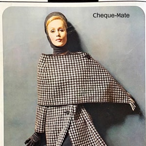 May include: A black and white houndstooth print coat with a matching scarf. The coat has a collar and a button closure. The model is wearing a black turtleneck sweater and black gloves. The image has the text "Cheque-Mate" at the top.