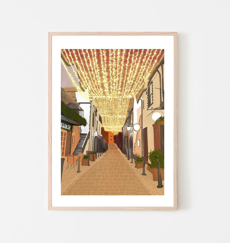 May include: A narrow, cobblestone street lined with buildings decorated with twinkling string lights. The street is empty, with the lights creating a warm, inviting atmosphere.