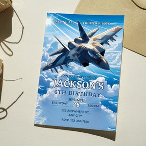 May include: A blue and white birthday invitation featuring a cartoon jet fighter in the sky. The invitation reads "Calling all fighter pilots" and "Join us to celebrate Jackson's 6th Birthday". The date is Saturday 28th September at 2:00 PM. The address is 123 Anywhere St., Any City. The RSVP number is 123-456-7890.