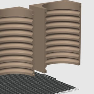 May include: Two beige, 3D-printed, semi-circular objects with a ridged, curved interior. The objects are rectangular with a rounded top and bottom. The objects are on a black and gray grid.