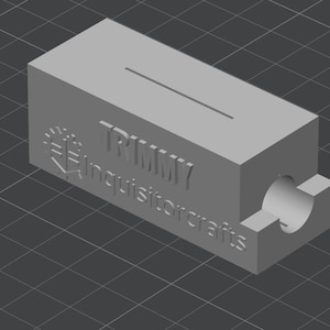May include: A gray, rectangular block with a slot and a cylindrical hole. The text "TRMMY" and "Inquisitorcrafts" are embossed on the side. The object is rendered in a 3D style.