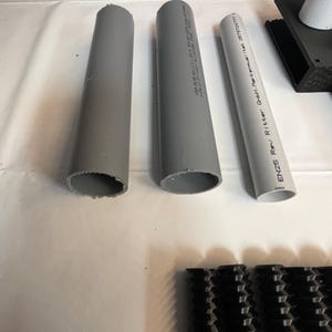 May include: Three gray PVC pipes with printed text on the side. The text on the pipe on the right reads "EN25 Rev Ritter GmbH-Markenmanual | L.Nr. 05732477".