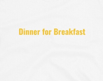 May include: White t-shirt with the text "Dinner for Breakfast" printed in yellow on the front.