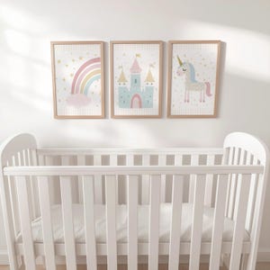 Pu&ograve; includere: Tre stampe artistiche incorniciate con un arcobaleno, un castello e un unicorno sono appese sopra una culla bianca. Le stampe hanno una cornice in legno chiaro e presentano colori pastello. La stampa dell'arcobaleno ha una nuvola rosa.