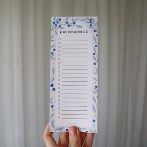 Peut inclure: Un bloc-notes blanc avec une bordure florale bleue et le texte "VERY IMPORTANT LIST" en haut. Le bloc-notes a un motif floral bleu avec des cercles blancs.