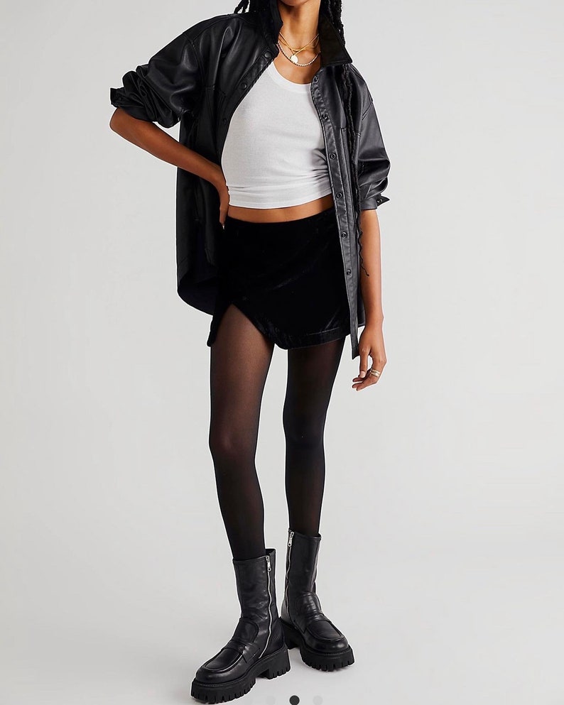 May include: A black velvet mini skirt with a side slit and a high waist. The skirt is paired with black tights and black leather boots.