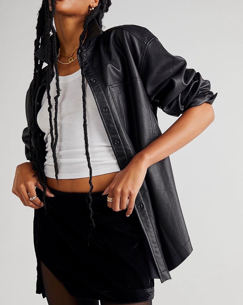 May include: A black faux leather shirt with a button-up front and a black velvet mini skirt. The skirt has a side panel of sheer fabric.