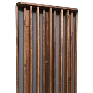 以下が含まれることがあります： グレーの布張りの木製音響パネル。パネルは、縦方向の木製スラットを使用したスラットデザインです。