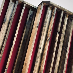 May include: Two wooden acoustic panels with red fabric lining the grooves. The panels are made of reclaimed wood with a rustic finish.