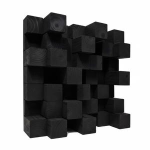 Puede incluir: Un panel difusor acústico cuadrado construido con numerosos bloques de madera maciza negra de diferentes profundidades. Los bloques están dispuestos en un patrón de cuadrícula, creando una superficie tridimensional con texturas de veta de madera visibles.