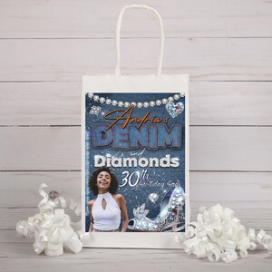 Op de afbeelding: Een witte papieren cadeauzak met een ontwerp in denimblauw en diamanten. De tas heeft de tekst "Andria's Denim and Diamonds 30th Birthday Bash".