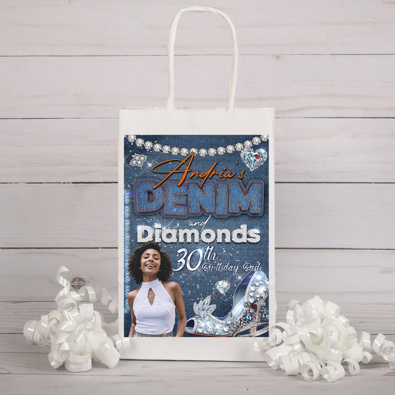 Op de afbeelding: Een witte papieren cadeauzak met een ontwerp in denimblauw en diamanten. De tas heeft de tekst "Andria's Denim and Diamonds 30th Birthday Bash".