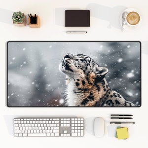 May include: A snow leopard with black spots looks up at the falling snow. The background is a blurry gray with white snow falling.