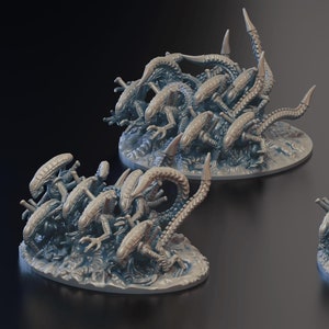 May include: A set of three miniature alien figures, each with multiple limbs and a sharp tail, are posed in a fighting stance on a circular base. The figures are painted in a gray and brown color scheme.