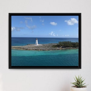 May include: A framed photograph of a white lighthouse on a small island in the middle of a turquoise ocean. The sky is blue with white clouds.