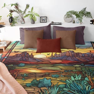 Puede incluir: Una cama con una funda nórdica de estilo vitral colorido que presenta un paisaje desértico con montañas, una puesta de sol y cactus. La funda nórdica está en una cama con almohadas marrones y moradas.