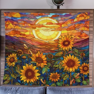 May include: A tapestry featuring a stained glass style sunset with a large sun and a field of sunflowers. The colors are vibrant and include shades of yellow, orange, red, blue, and green.