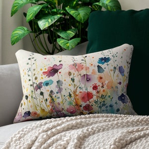 May include: A white pillow with a watercolor floral print featuring colorful flowers and green leaves on a white background.