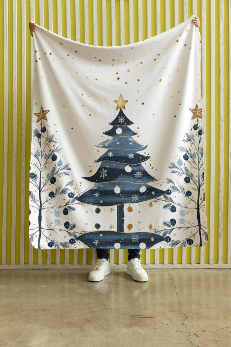 May include: A white fleece blanket with a blue and gold Christmas tree design. The tree is decorated with gold stars, blue ornaments, and white snowflakes. The blanket is perfect for adding a festive touch to your home decor.