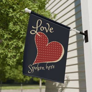 May include: A navy blue garden flag with a red heart with white polka dots and the text "Love Spoken Here" in a cream colour.