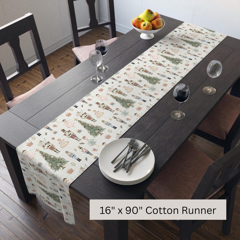 May include: A cotton table runner with a festive pattern of nutcrackers and Christmas trees. The runner is 16 inches wide and 90 inches long, displayed on a dark wood table set for a meal. Wine glasses and a plate with silverware are visible.