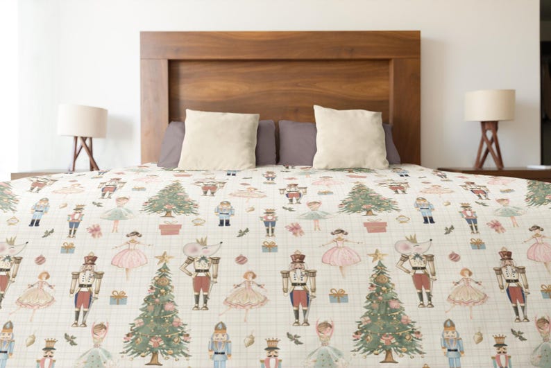 May include: A cream-colored bedspread featuring a repeating pattern of nutcrackers, ballerinas, mice wearing crowns, decorated Christmas trees, and gift boxes. The design is set against a subtle grid background with small red and green accents.