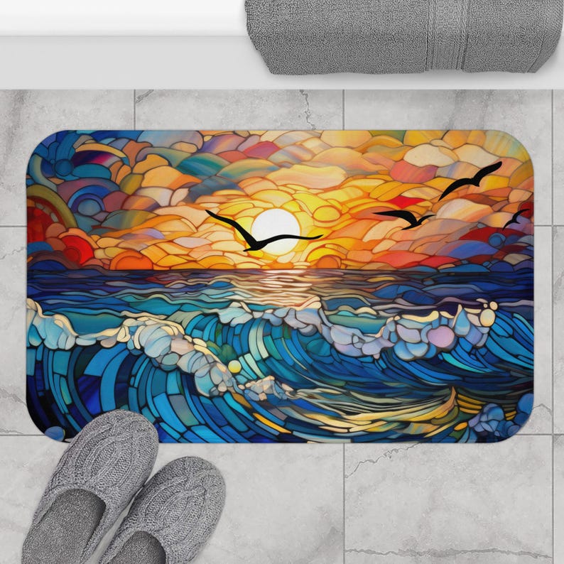 Puede incluir: Una colorida alfombra de ba&ntilde;o estilo vitral con una puesta de sol sobre el oc&eacute;ano y tres p&aacute;jaros volando en el cielo. La alfombra es azul, amarilla, naranja y roja.