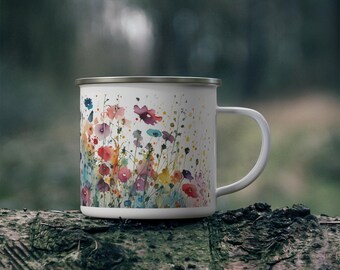 May include: A white enamel mug featuring a colorful watercolor-style print of various wildflowers in shades of red, pink, blue, and yellow. The mug has a smooth white finish, a silver-toned rim, and a curved handle extending from the right side.