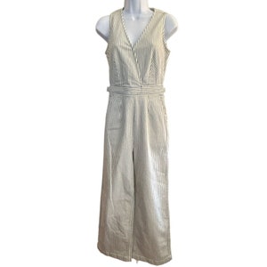 Könnte beinhalten: Ein weiß-schwarz gestreifter, ärmelloser Jumpsuit mit V-Ausschnitt und weitem Bein.