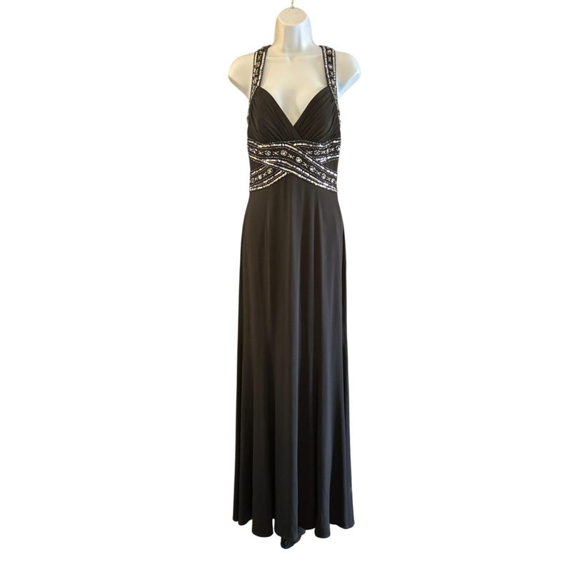Puede incluir: Un vestido largo, negro, sin mangas con escote en V y una cintura con cuentas.