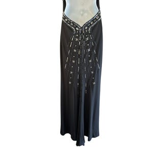 Puede incluir: Un vestido negro maxi con un dise&ntilde;o de cuentas. El vestido tiene un escote en V y un corpi&ntilde;o ajustado. La falda es fluida y tiene una ligera forma de A.