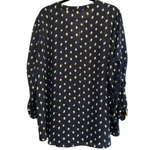 May include: A navy blue blouse with a white polka dot pattern. The blouse has a V-neck and long sleeves.