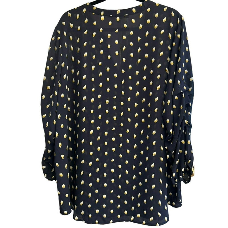May include: A navy blue blouse with a white polka dot pattern. The blouse has a V-neck and long sleeves.