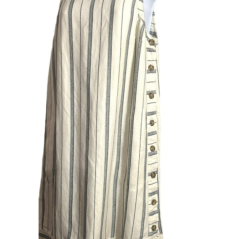 Puede incluir: Un vestido sin mangas de rayas blancas y negras con cierre de botones en el lateral.