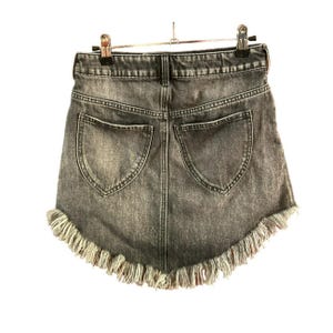 May include: A dark grey denim skirt with a frayed hem. The skirt has two back pockets.