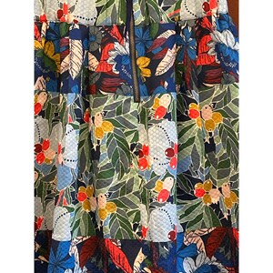 Puede incluir: Una falda de estampado floral azul, verde, rojo y blanco con cierre de cremallera. La falda tiene una tela texturizada y un dise&ntilde;o plisado.