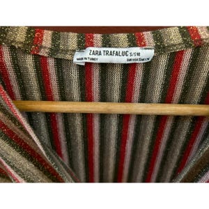 K&ouml;nnte beinhalten: Ein gestreiftes Strickoberteil mit roten, goldenen und grauen Streifen. Das Etikett lautet "ZARA TRAFALUC S/S'18" und "MADE IN TURKEY" mit Gr&ouml;&szlig;eninformationen "EUR/USA S/M/L/XL".